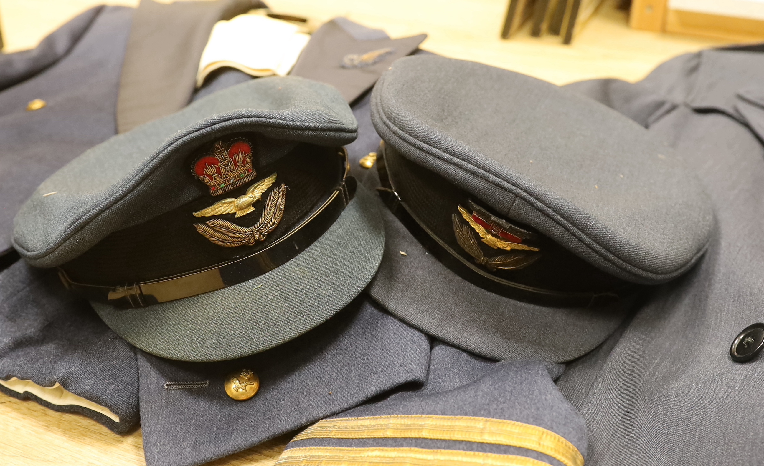A collection of post-war RAF uniforms, comprising; two caps, double-breasted overcoat, dress uniform of jacket, trousers and gloves, two sets of jacket and trousers with ribbons for WWII awards, plus a pair of navigator’